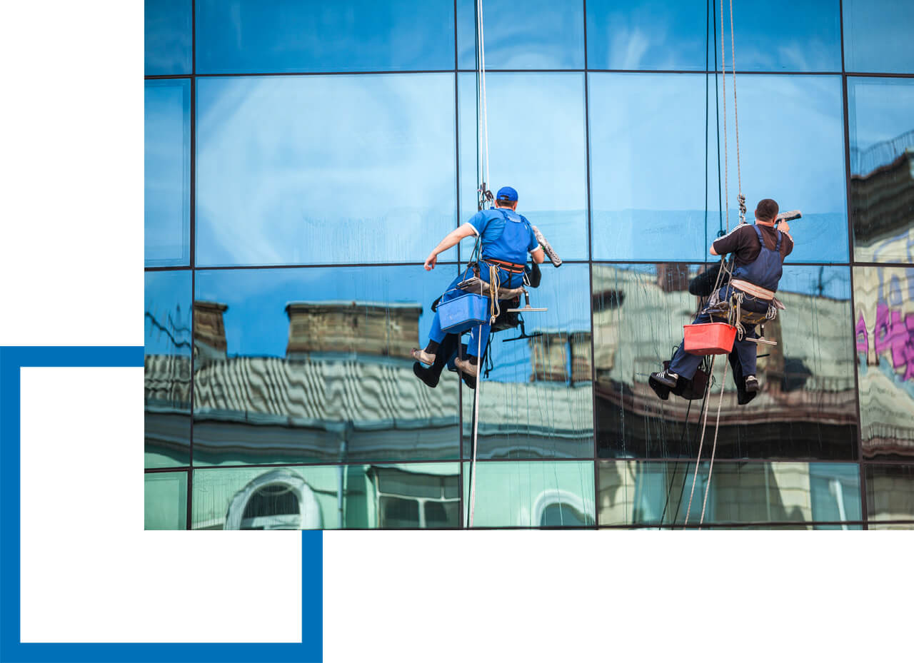 Zwei Fensterreiniger hängen gesichert an einer großen Fensterfassade