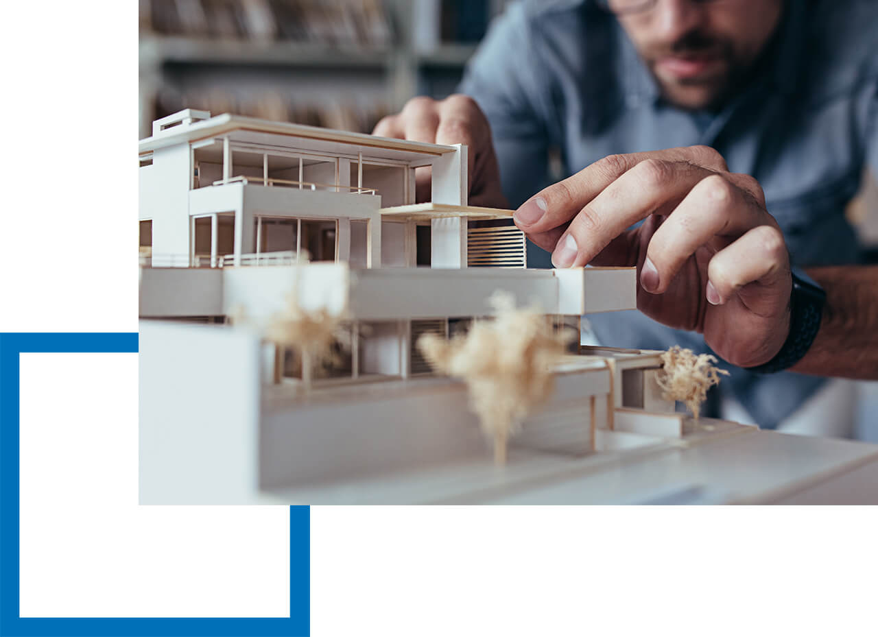 Berufshaftpflichtversicherung für Architekten ist unverzichtbar! Person arbeitet präzise an einem Architekturmodell eines modernen Gebäudes.