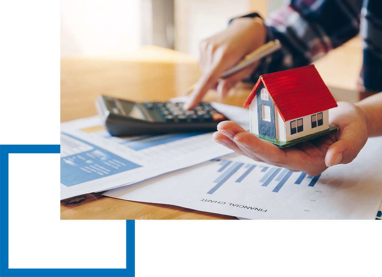 Voraussetzung für die Zulassung als Immobiliardarlehensvermittler. Hand hält ein Miniaturhaus mit rotem Dach über Finanzunterlagen, während die andere Hand Zahlen in einen Taschenrechner eingibt.