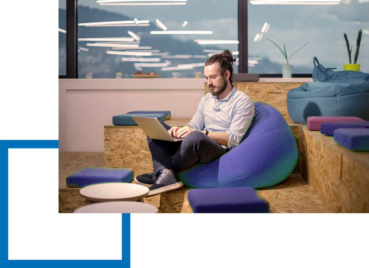 Welche Risiken können Softwareentwickler absichern? Mann arbeitet entspannt mit Laptop auf Sitzsack in modernem Büro.