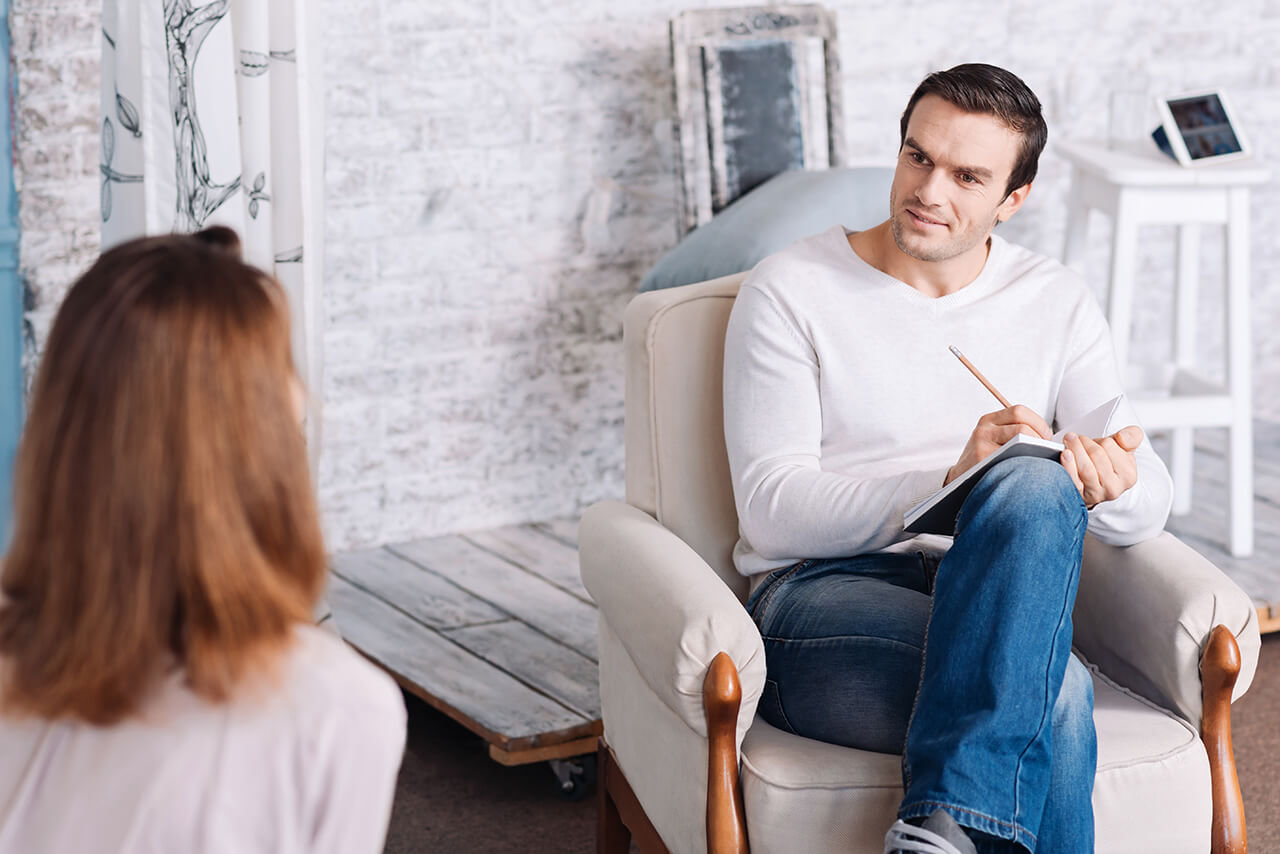 Ein Psychotherapeut führt mit einer Patientin in einer ruhigen Umgebung ein Gespräch.