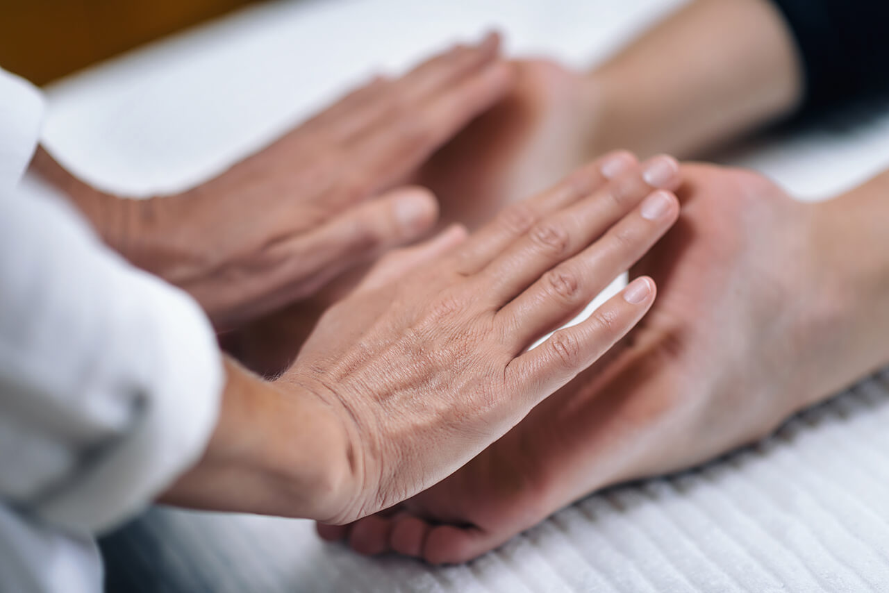 Reiki-Behandlung mit Händen über dem Fuß.