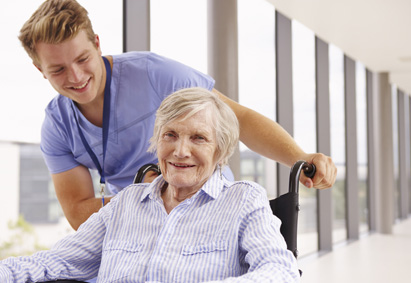 Krankenpfleger kümmert sich um eine Seniorin im Rollstuhl