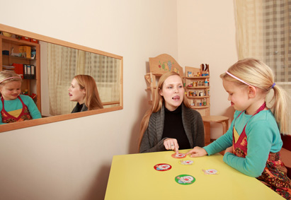 Logopädin ist in der Therapiestunde mit einem Kind