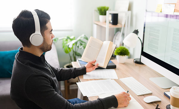 Haftpflichtversicherter Dolmetscher bei seiner Arbeit dem Übersetzen am PC mit Buch