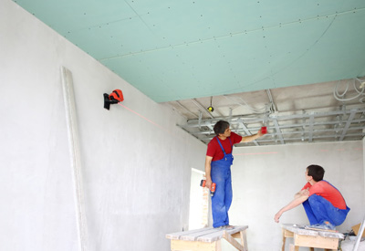 Zwei Handwerker montieren Gipsplatten an die Decke